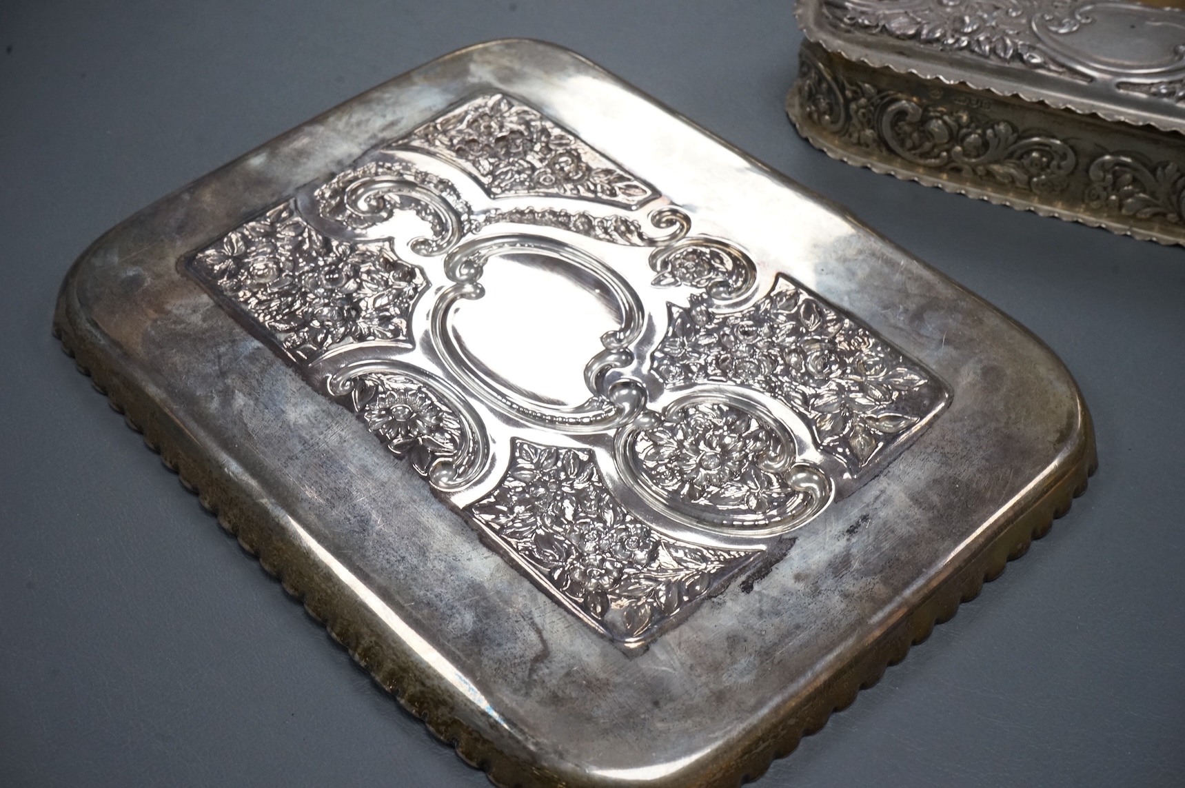 An early 20th century repousse silver dressing table tray by William Comyns & Sons Ltd, London, 1901, 25.1cm, together with a matching oval trinket box, London, 1900, 16.6oz (a.f.).